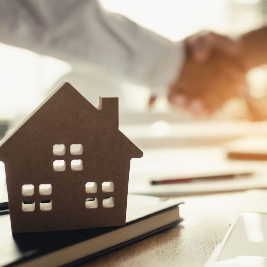 construction worker shaking hands with customer after finishing up business meeting to start up project contract in office center at construction site behind house model, home loan contract concept